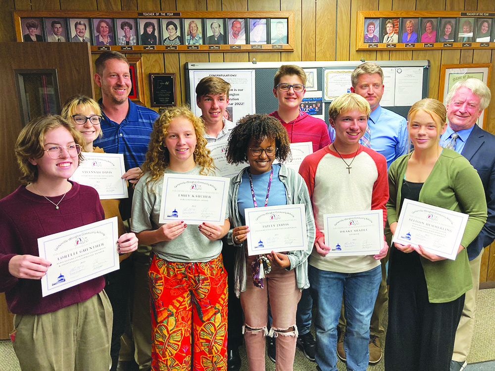 A group of students and educators stand together to show off certificates of recognition