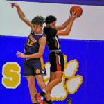 Two high school basketball players competing for the ball