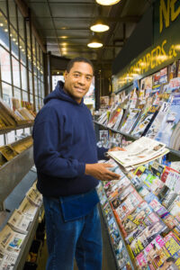 A person holding a newspaper next to a newsstand